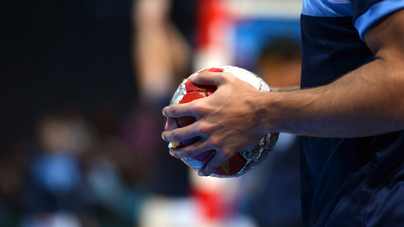 Seitenansicht einer Hand eines Handballspielers mit einem Ball in der Hand.